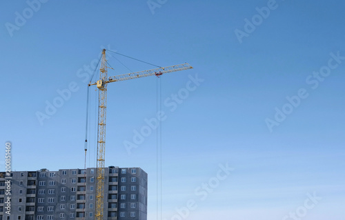 Construction of a multi-storey building. Crane on sky background.