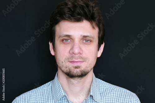 Portrait of young handsome man in plaid short looking at camera.