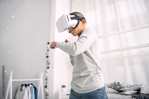 Unbelievable experience. Earnest afro american boy wearing VR headset while moving hands