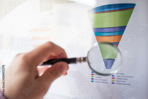 Colourful sales funnel chart under a magnifier lens for marketing data analysis photo