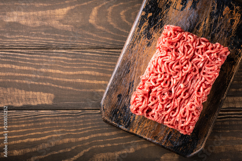 Fotografía Overhead shoot of fresh raw beef minced meat on dark wooden board