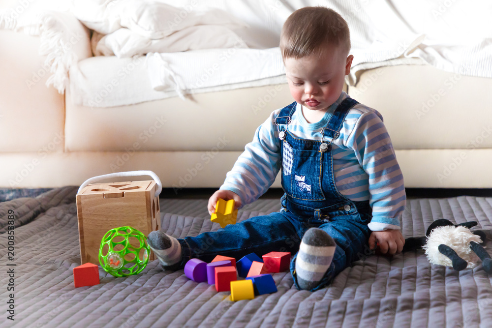 Portrait of cute baby boy with Down syndrome playing in home living room Portrait of cute baby boy with Down syndrome playing in home living room