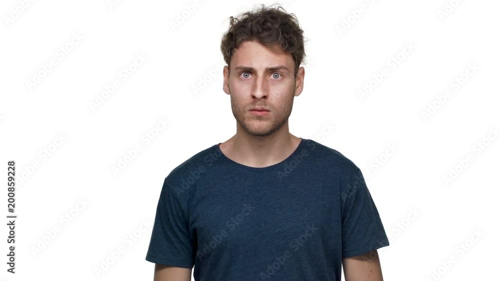 Portrait of unshaved caucasian guy posing with strict gaze and asking keep silence putting index finger on lips, isolated over white background. Concept of emotions Portrait of unshaved caucasian guy posing with strict gaze and asking keep silence putting index finger on lips, isolated over white background. Concept of emotions