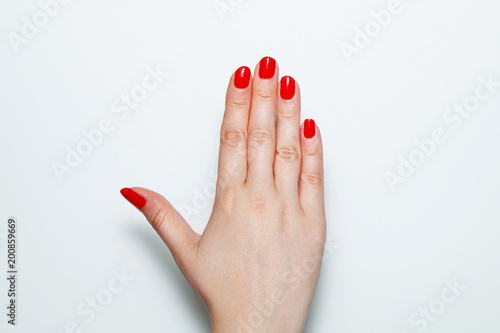 Canvas Print Female palm with red nails painted on a white background