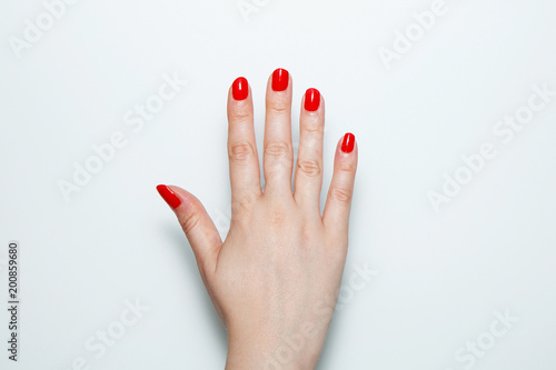 Tela Female palm with red nails painted on a white background