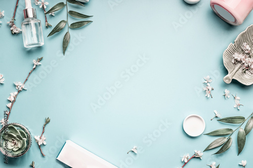 Facial cosmetic products, leaves and cherry blossom on blue table