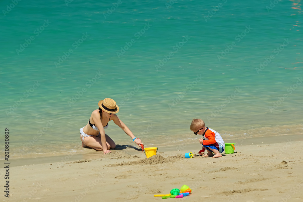 Two year old toddler playing with mother on beach Two year old toddler playing with mother on beach
