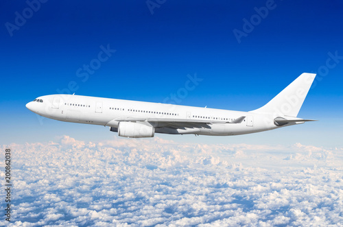 Passenger airplane fly on a hight above overcast clouds and blue sky.