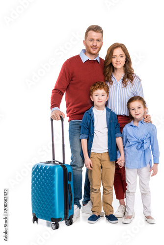 happy redhead family with suitcase standing together and smiling at camera isolated on white