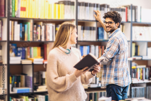 people  knowledge  education and school concept - happy student couple with books in library