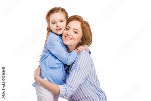 beautiful happy mother and daughter hugging and smiling at camera isolated on white