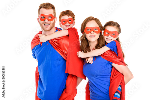 super parents piggybacking happy kids in masks and cloaks isolated on white