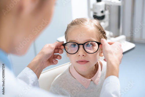 optometrist and little kid in glasses in optics