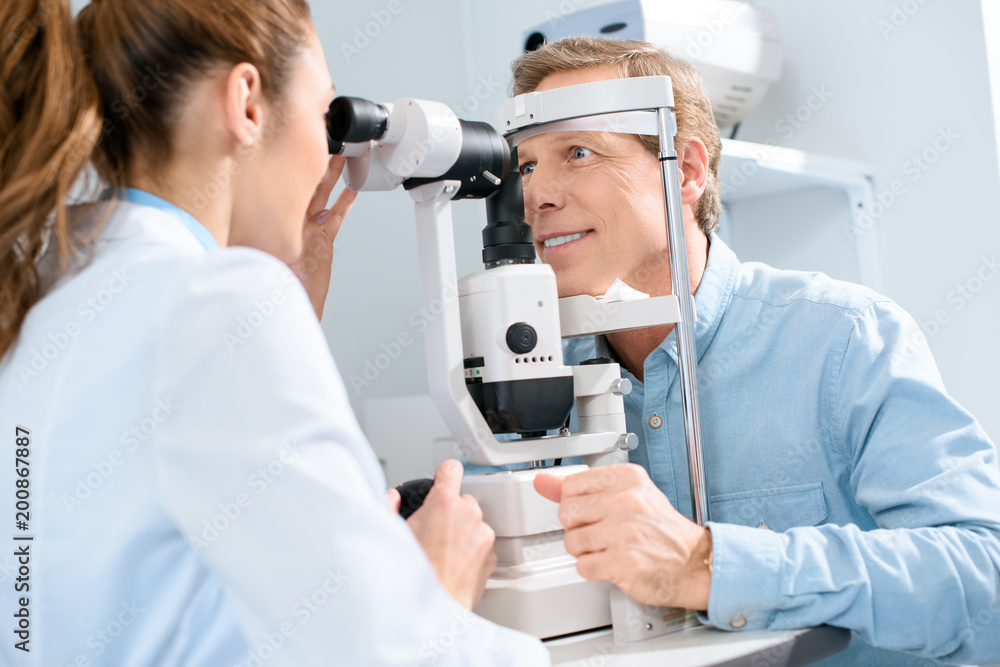 professional female optician examining man with modern visual equipment professional female optician examining man with modern visual equipment