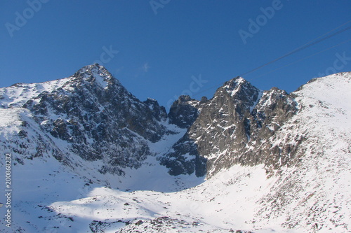 a panorama of snow-capped peaks of the mountain ridge of the High Tatras under the rays of the winter sun.