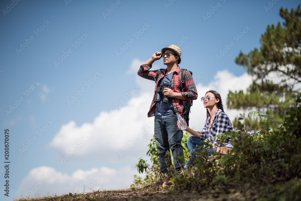 Thoughtful hiking couple looking away while relaxing in forest