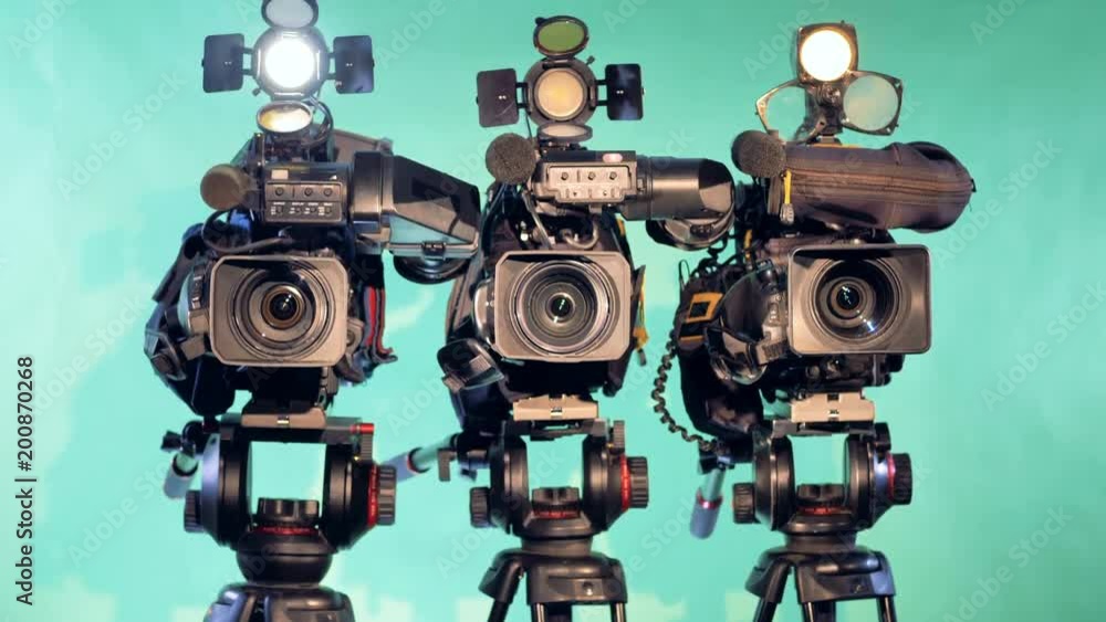 Three video cameras are standing in a studio Three video cameras are standing in a studio