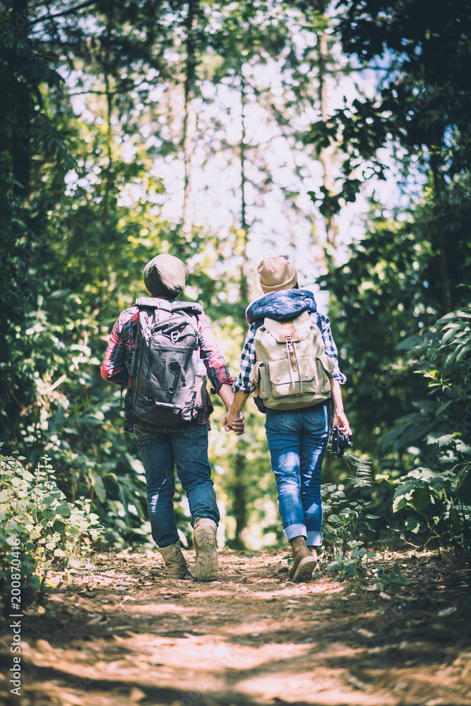 Young couple walking with backpacks in forest. Adventure hikes, Enjoy holidays together,