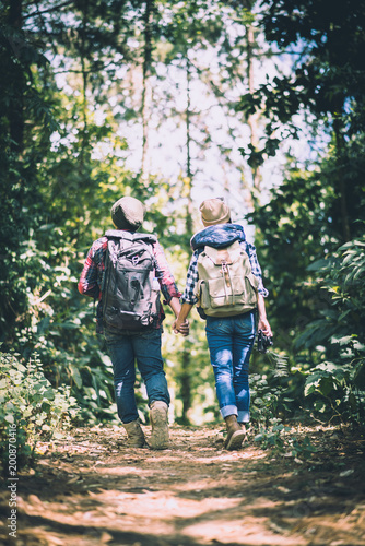Young couple walking with backpacks in forest. Adventure hikes, Enjoy holidays together, © Johnstocker
