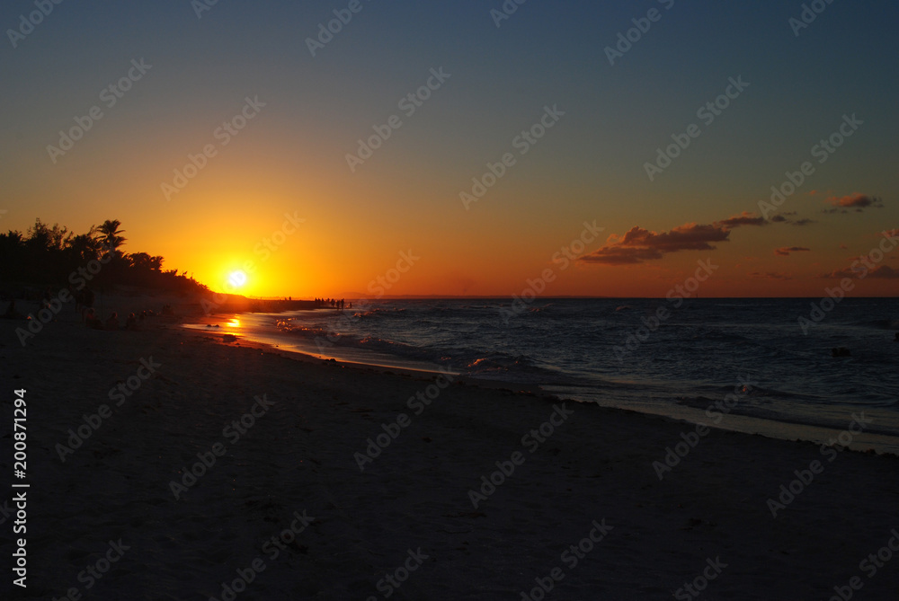 Sunset on the beach in Cuba. Orange sun on the horizon.