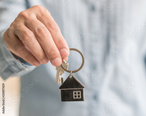 House key in real estate sale person, landlord or home Insurance broker agent's hand giving to buyer customer for new family property assurance concept