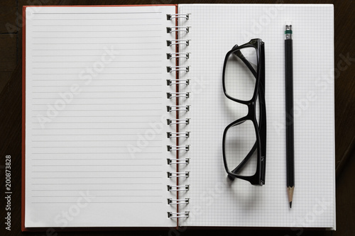 pencil and glasses on open book with line on brown wood
