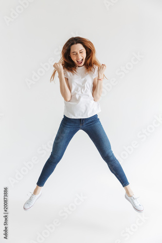 Full-length image of Happy woman in t-shirt jumping and rejoices