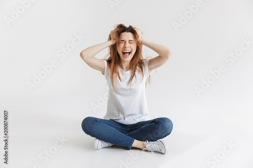Angry woman in t-shirt sitting on the floor and screaming