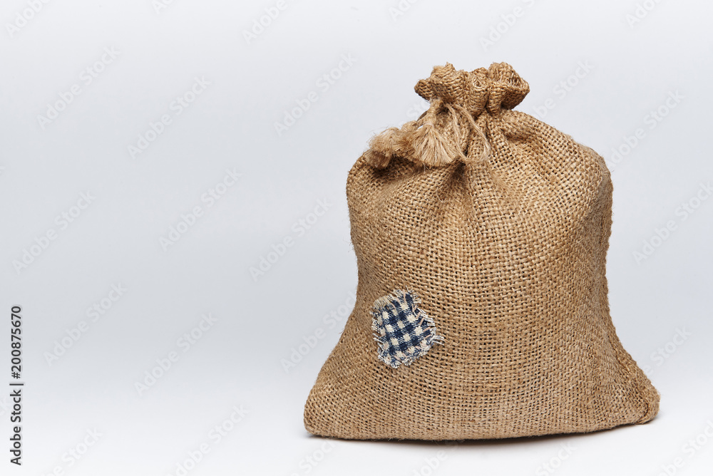 A filled bag of burlap with a patch on a white background. A filled bag of burlap with a patch on a white background.