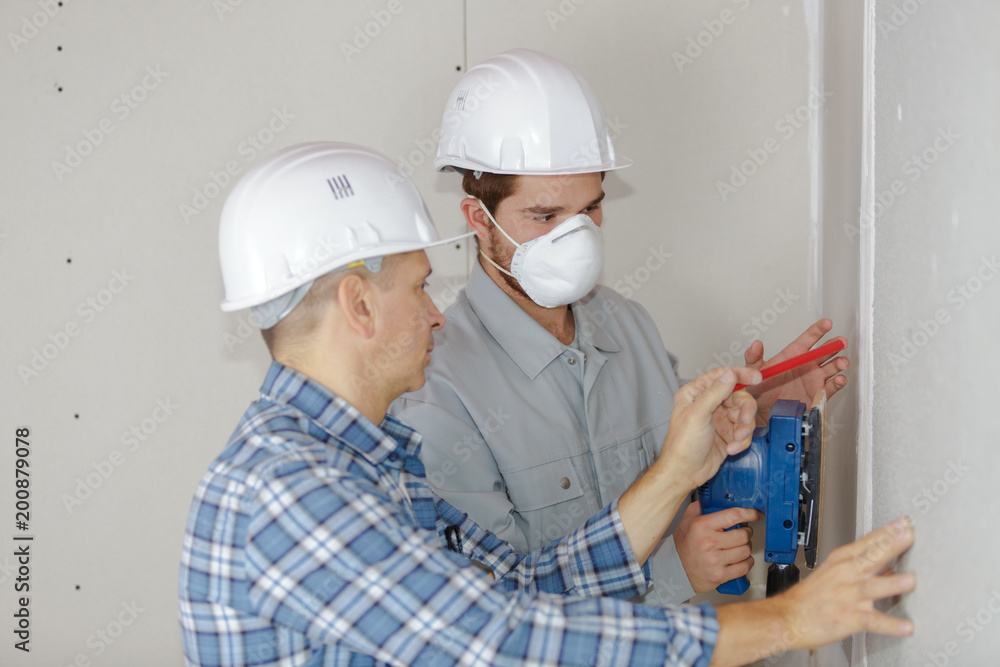 home improvement workers in protective mask working with sander