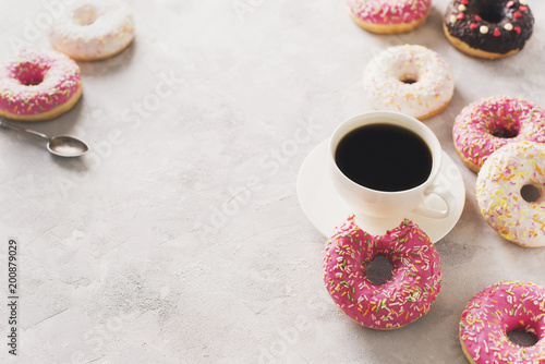 Sone pink and white donuts with cup of coffee over white stone texture