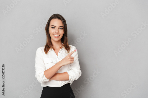 Happy young business woman pointing.