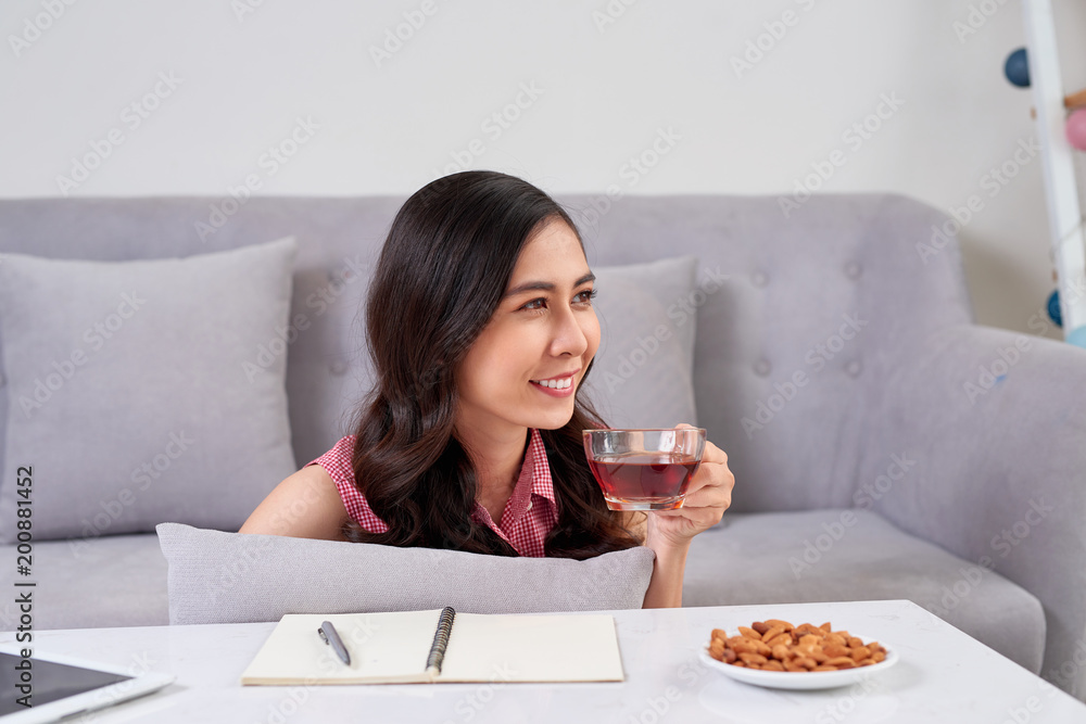 Young asian woman enjoying a tea break and snack while working at home. Young asian woman enjoying a tea break and snack while working at home.