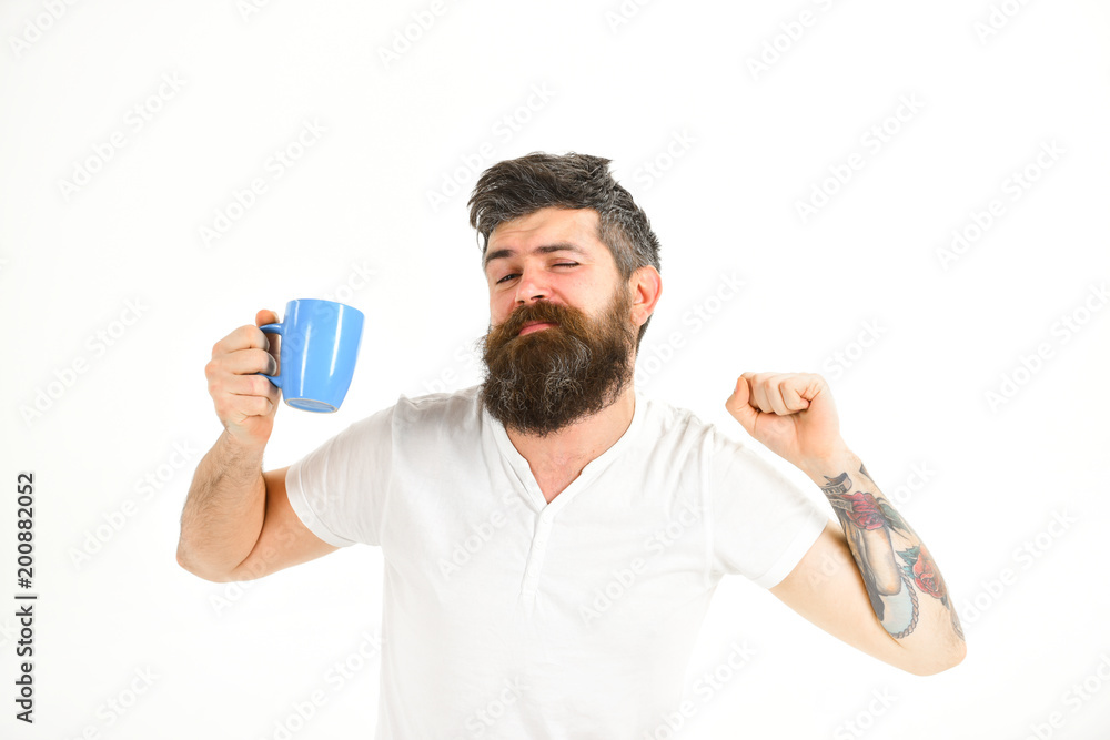 Sleepy hipster with beard holds mug in hand. Sleepy hipster with beard holds mug in hand.