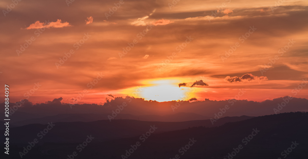 sunset scene with sun fall and ray light, clouds in background, warm colorful sky with soft clouds