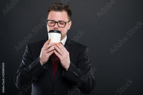 Portrait of business man smelling cup of takeaway coffee.