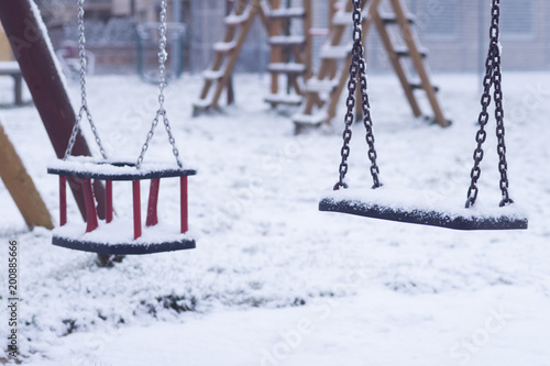swing for children in winter. playground near the house.