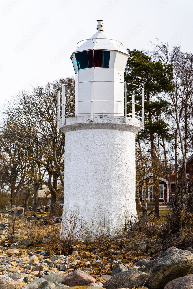 Small and white lighthouse in coastal landscape. Location Ispeudde on Oland, Sweden.
