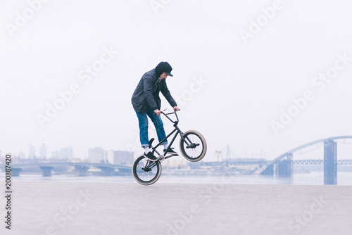 BMX freestyle. Young BMX bicycle makes tricks on the background of a city landscape