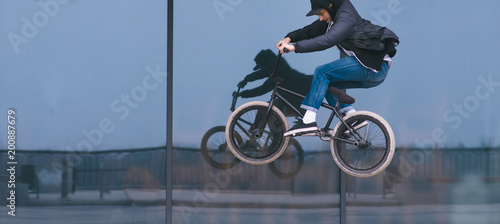 A man makes a trick on BMX on a black background. BMX freestyle. The teen is flying on a bike.