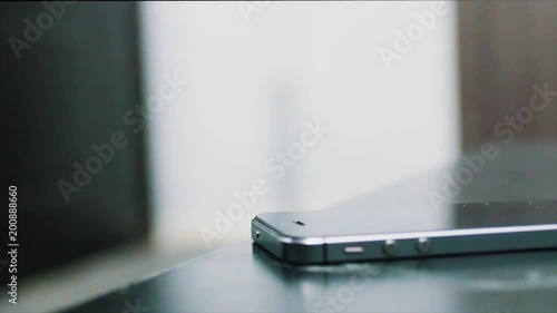 Close up of Young man hand puts mobile phone on wooden desk. Putting down cell phone on wooden table. Human hand places on table cellphone with completely discharged battery, close up view