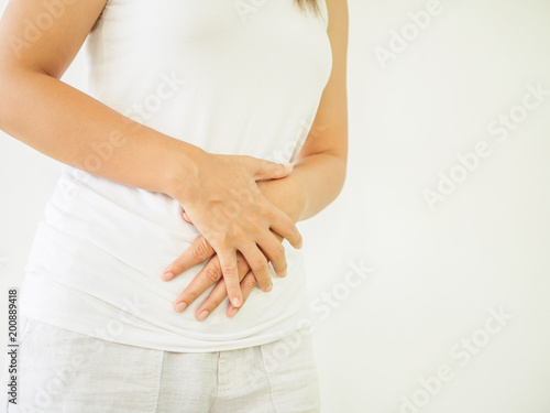 Woman having a stomachache, or menstruation pain with white background. Health care and medical concept. © Siam