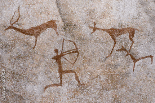 An image of a hunt on a cave wall drawn by an ancient human ocher. archeology.