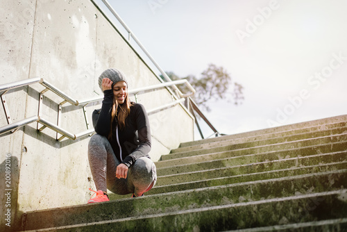 Sporty woman taking a rest during urban outdoor morning fitness and running workout.