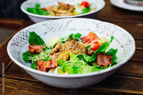 Delicious fresh salad with vegetables and bacon on a wooden table