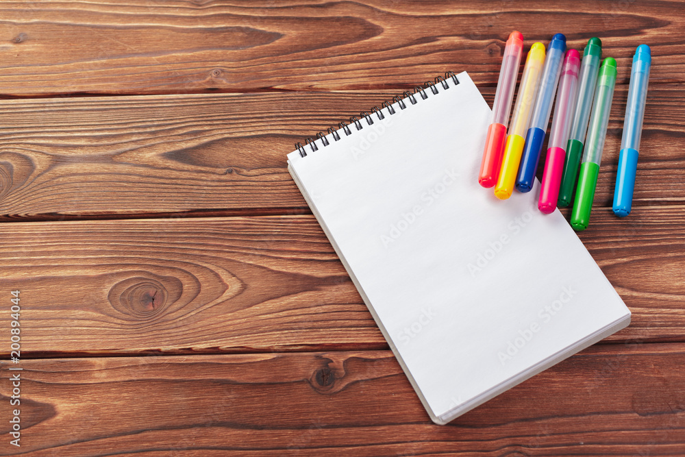 Office desk table top view. Notepad with blank pages on wooden table Office desk table top view. Notepad with blank pages on wooden table
