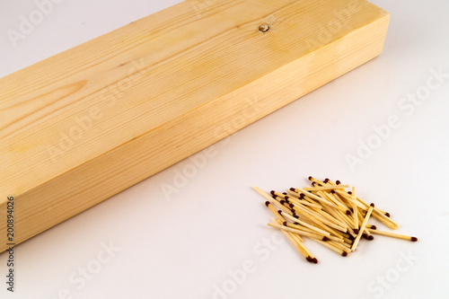 Wooden block with a processed surface, near which a hill of matches on a white background.