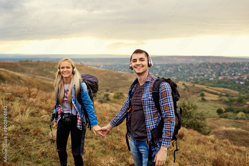 Happy couple of tourists in headphones on nature. Happy couple of tourists in headphones on nature.