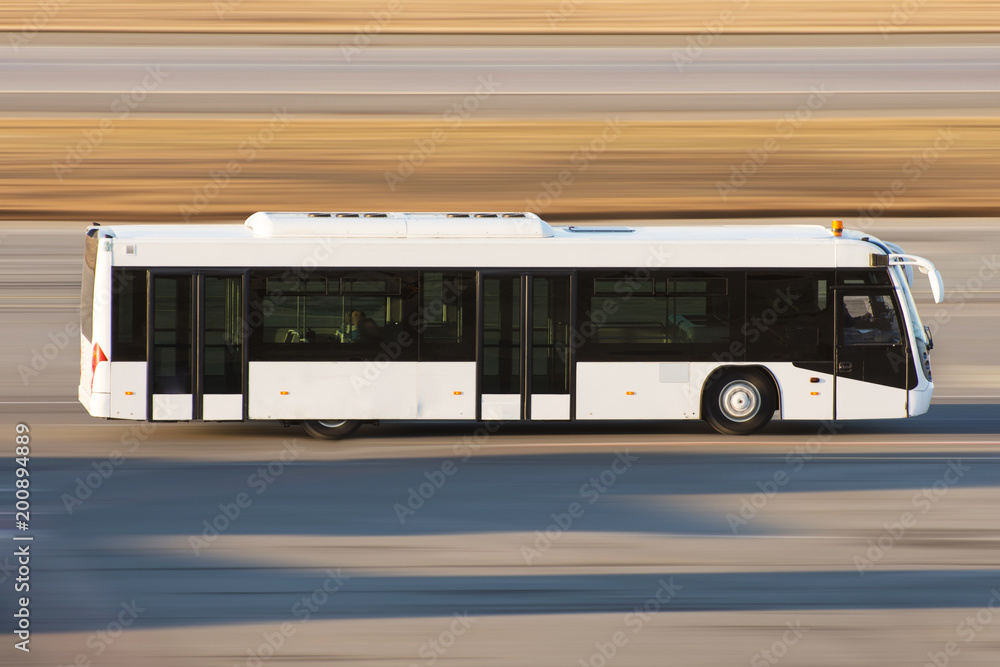 Modern transport bus on asphalt rides at high speed.