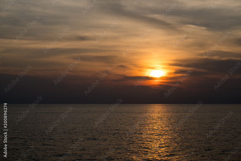 Sunset at sea with the red sky and reflection of the sun in the surface.